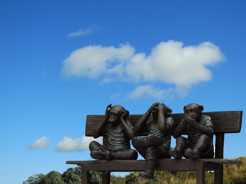 Three monkeys sitting on a bench, embodying the see no evil, hear no evil, speak no evil proverb.